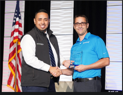 Daniel Galindo, SVP, CRA and Strategy Director, Woodforest National Bank, accepting the Wolters Kluwer's 2019 Community Impact Award from Nick Hammerstad, VP of Sponsor Acquisition for Banzai Inc., the award sponsor