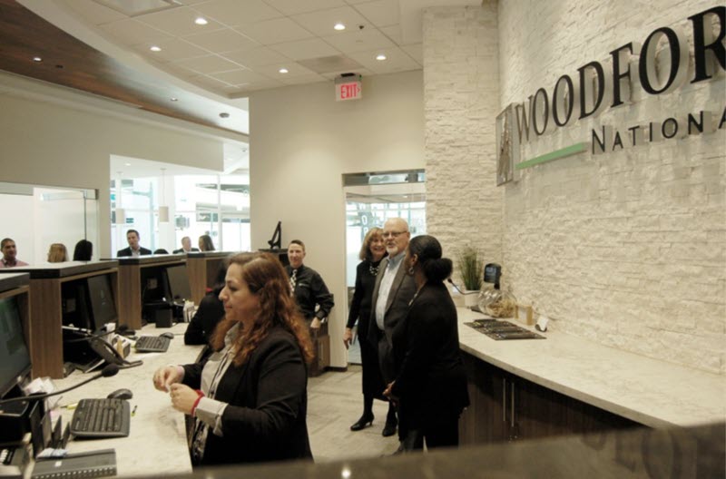 Jay Dreibelbis, President and CEO (center), visits with employees behind the teller lobby during soft opening of the newly re-built Woodforest National Bank building in Downtown Conroe. (Photo by Liz Grimm)