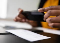 Una persona tomando una foto a un cheque con su teléfono móvil